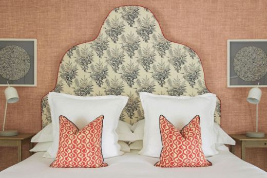 Barron and Larcher Bouquet floral linen fabric in dark indigo and orange, used on a tall decorative headboard in a hotel, designed by Claudia Starr.