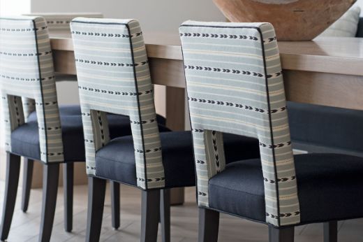 Upholstered dining chairs designed by TH2 Designs, featuring Bow and Arrow Woven Fabric in aqua colourway on the back of the chair, photographed by Olivia Karsenbarg, adding vibrant texture and style to the dining space.