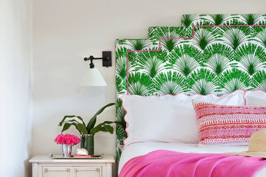 Bright green and pink bedroom featuring an Art Deco-shaped headboard upholstered in Brisa Feather Fan green fabric, accented with pink accessories. Photography by Donna Griffith.