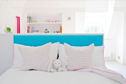 Broken stripe linen fabric cushions in a children's bedroom with a blue headboard. Design by Cloud Studios.