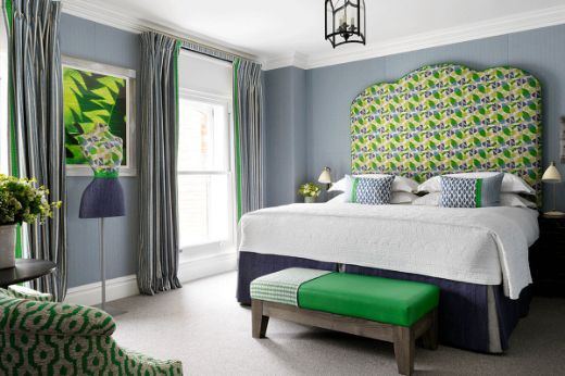 Location at Firmdale Hotels, photographed by Simon Brown, featuring Cactus Flower green fabric on a tall headboard in a room with green and blue hues, complemented by a mannequin. Designed by Kit Kemp's Design Studio