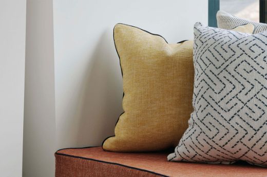 Close up image of Frieda Lemon and Freida terracotta cushions with vertelli piping nero.