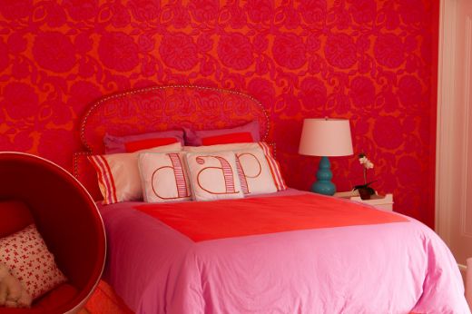 Hot pink fuchsia floral wallpaper in a bedroom interior, featuring a vibrant nature-inspired pattern, with a matching upholstered headboard. Designed by Michael Szell for Christopher Farr Cloth.
