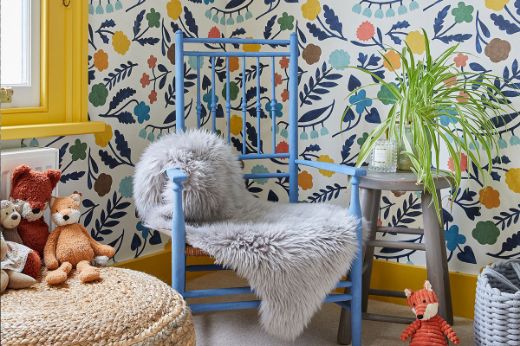 Children's room featuring Array Indigo Floral Wallpaper by Makoto Kagoshima, creating a whimsical and playful corner with a yellow painted window, blue painted chair, teddy bears, and a jute footstool. Design by Foxglove House Interiors, photographed by Chris Snook