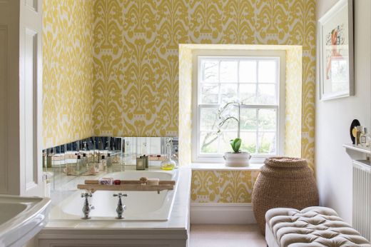 Mimosa Colourway - Yellow damask patterned wallpapered bathroom with sash window, mirrored tiles on the sink, creating a classic interior design look.