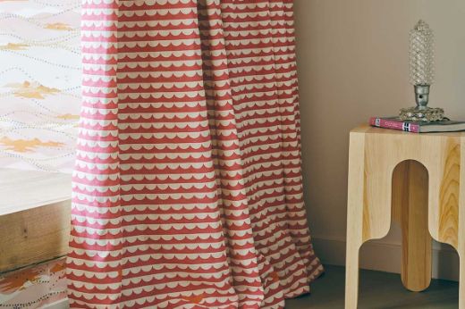 Hot Pink scallop wave patterned curtain in a cozy room with a wooden table. Photography by Christopher Horwood