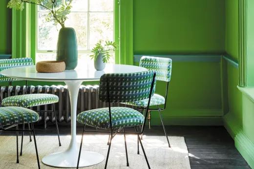 Cremaillère green geometric print fabric on dining chairs, set in a fresh and inviting Georgian dining room with sash windows. The walls are painted in Little Greene's Sage Green, enhancing the space with a sophisticated and timeless feel.