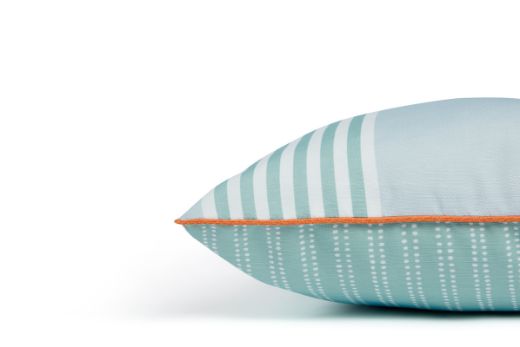 Side view of The Hudson Stripe Outdoor Cushion featuring a bold and intricate stripe design in Turchese blue and white, with orange vertelli piping trim offering contrast for a modern yet timeless look for outdoor spaces.