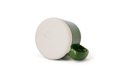 Vorster & Braye Ceramic Mug in Grass Green laid down, showcasing the bottom imprinted with the Vorster & Braye x Christopher Farr Cloth logo, highlighting its artisanal craftsmanship.
