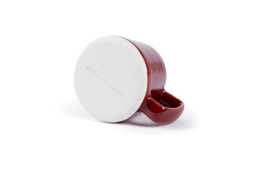 Vorster & Braye Ceramic Mug in Ruby Red laid down, showcasing the bottom imprinted with the Vorster & Braye x Christopher Farr Cloth logo, highlighting its artisanal craftsmanship.